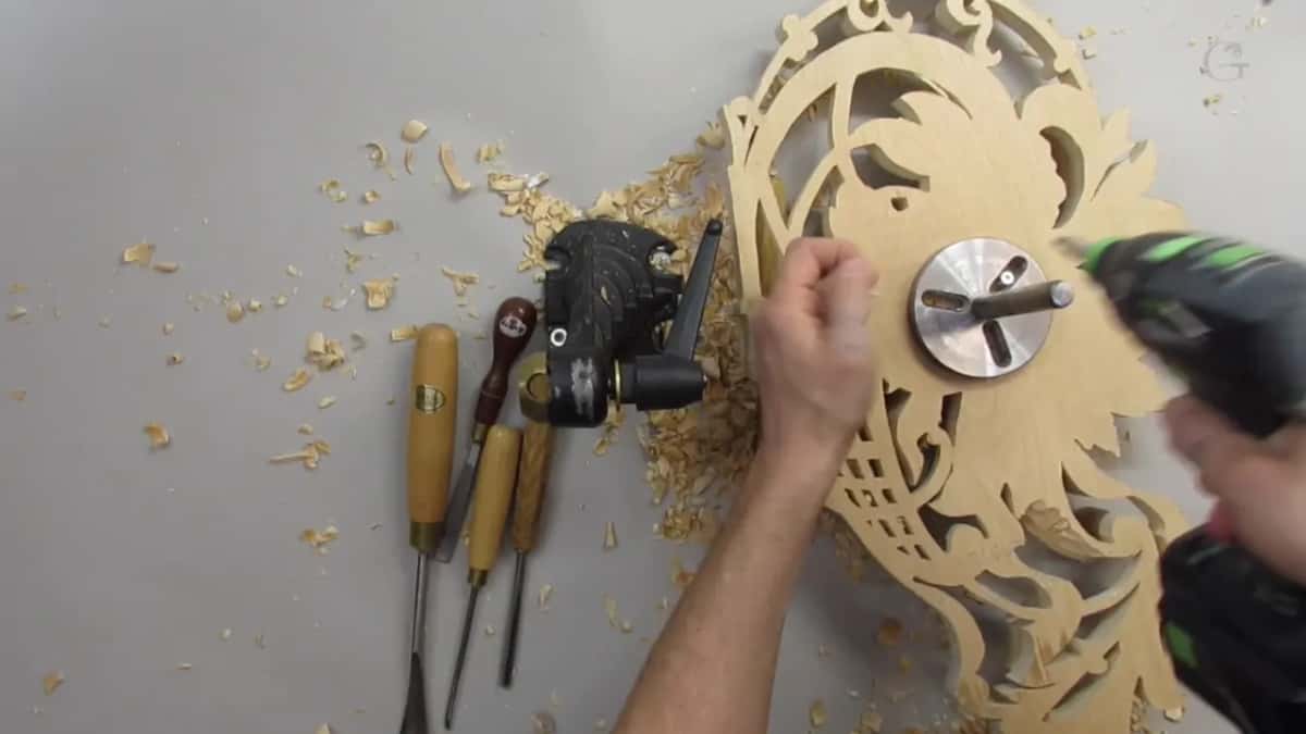 Cordless driver at the round plate in the middle of the bare back, with the vise head and gouges lying beside it