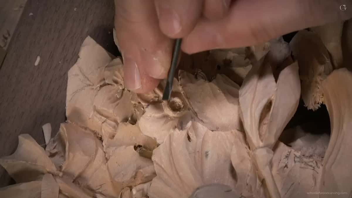 A thin tool working inside a carved flower