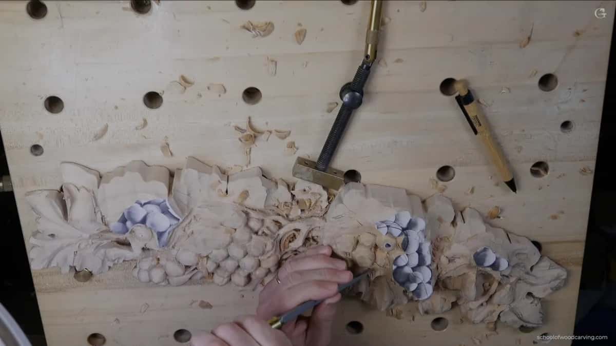 One hand works a tool near the middle of the panel, a pen lying above