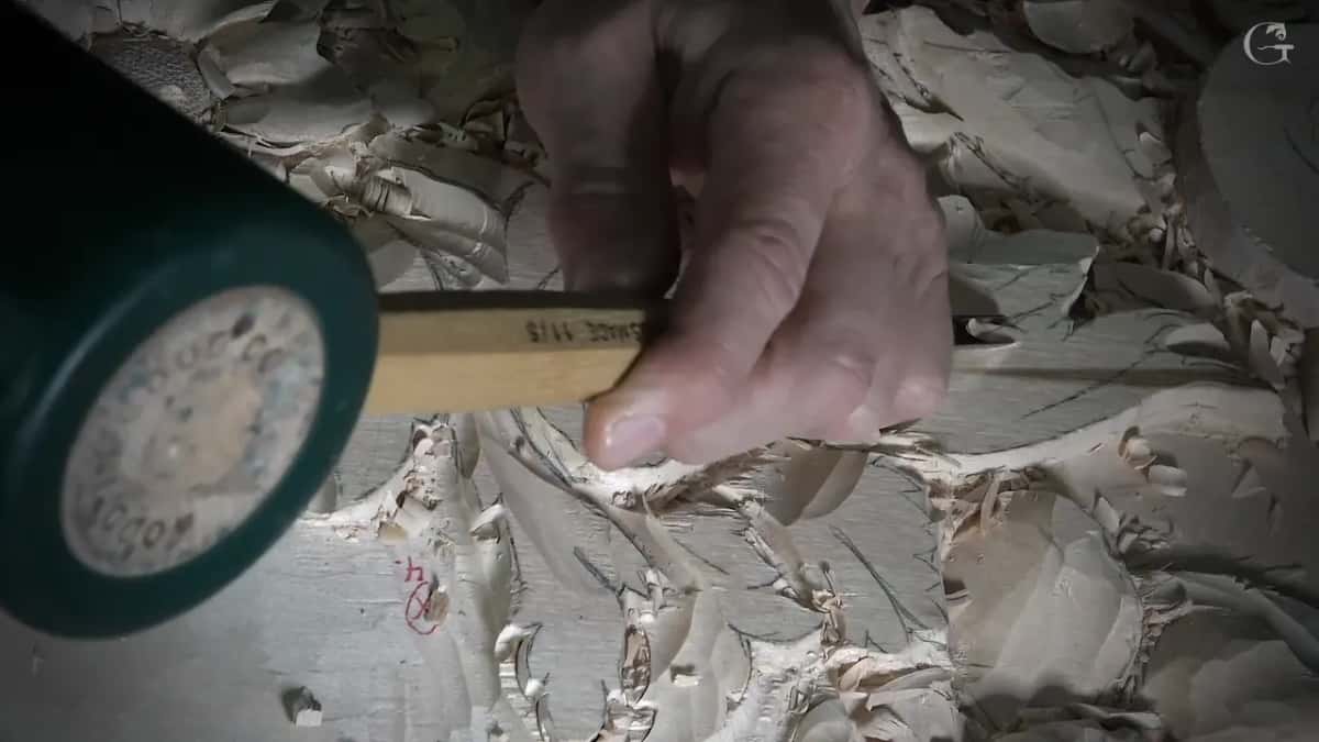 Green mallet meeting the end of a yellow handle over roughed leaves