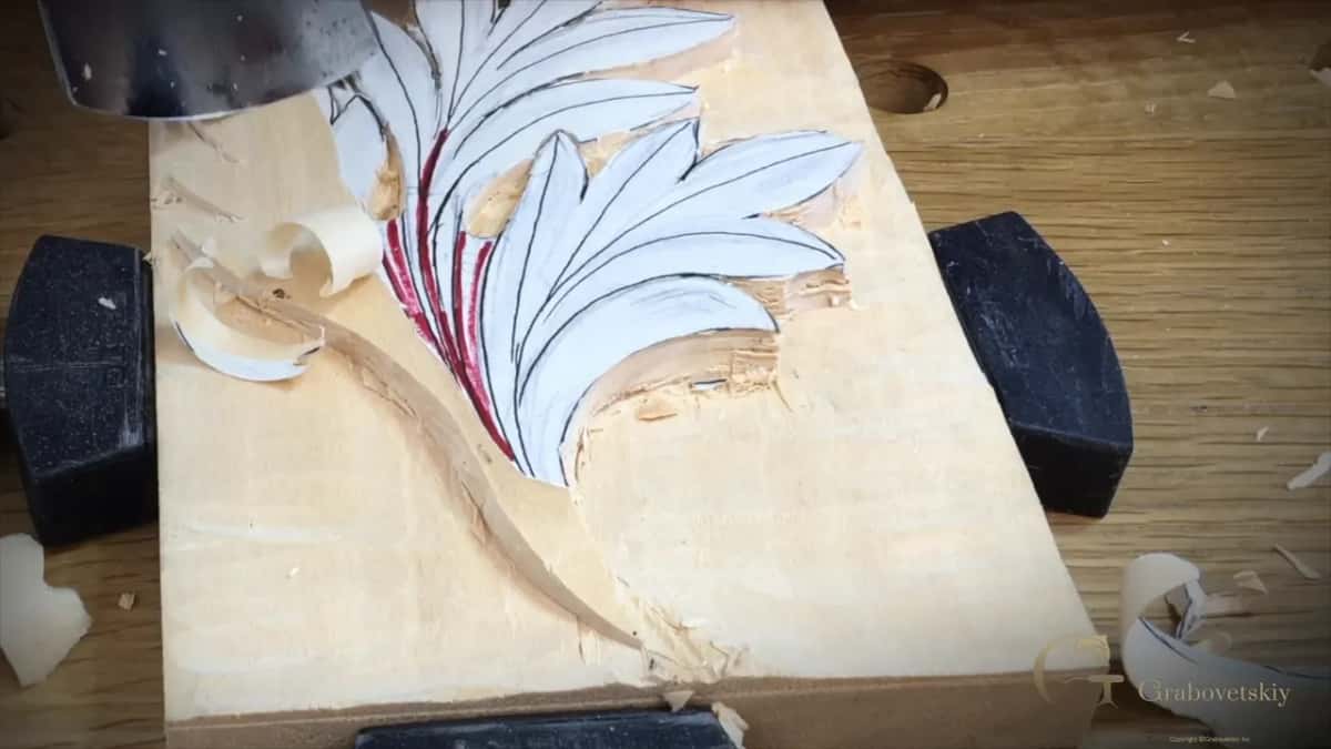 Curled shavings beside the leaf, its left side already lowered and the paper gone there
