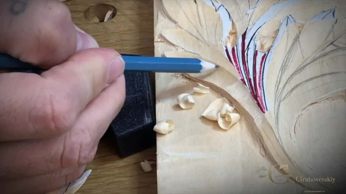 Close view of a blue pencil tip on the wood beside red marker lines