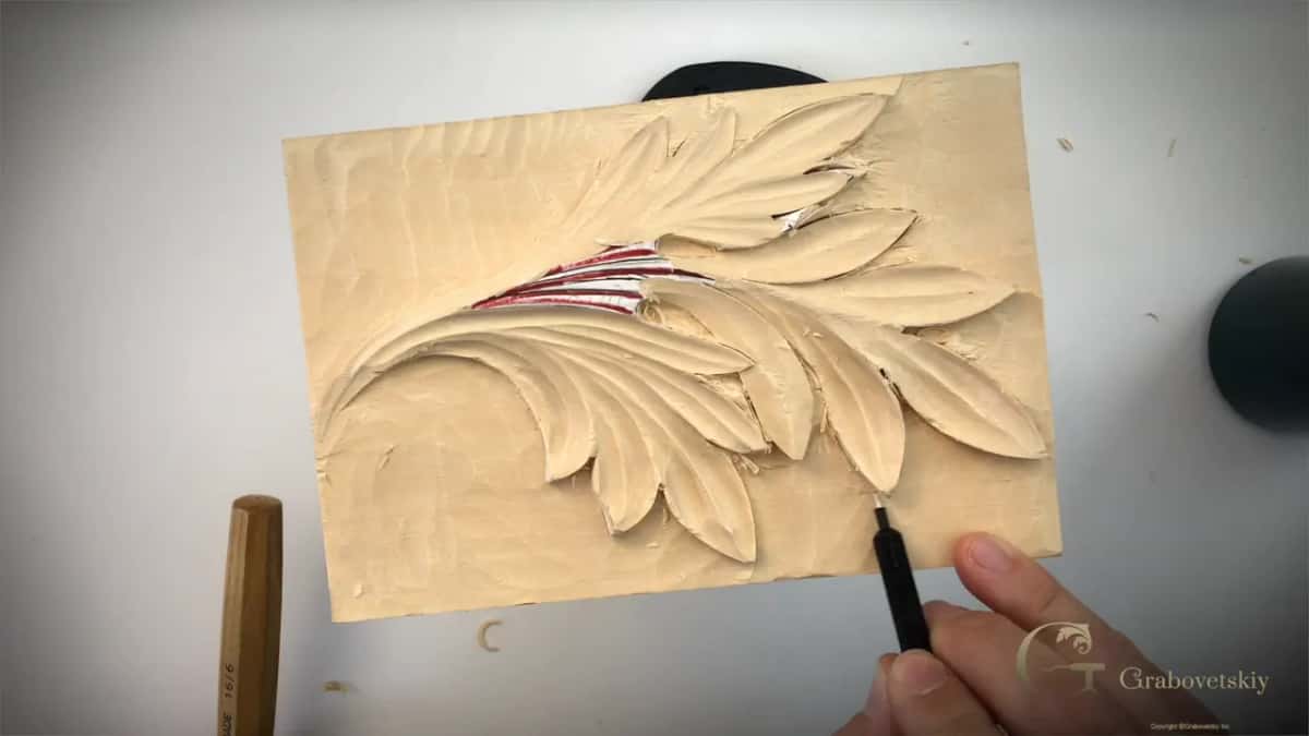 From above, a V tool at the lower edge of the leaf and a tool handle lying on the left