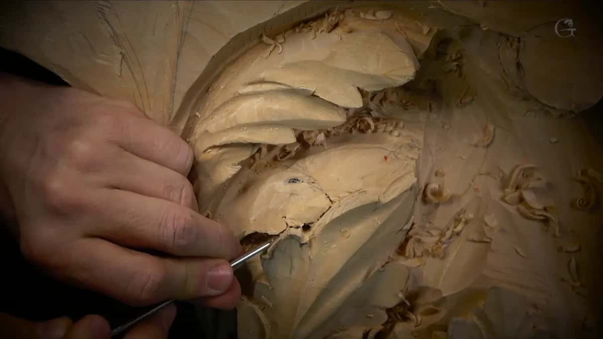 Fingers steer a thin veiner along a pale lobe, close to a small dark hole.