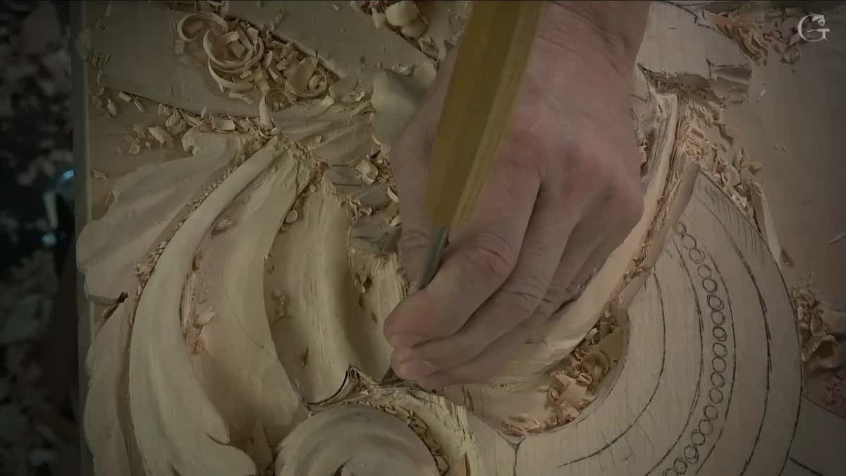 Close view of the tool standing straight down against the rim of the scroll, one hand around it