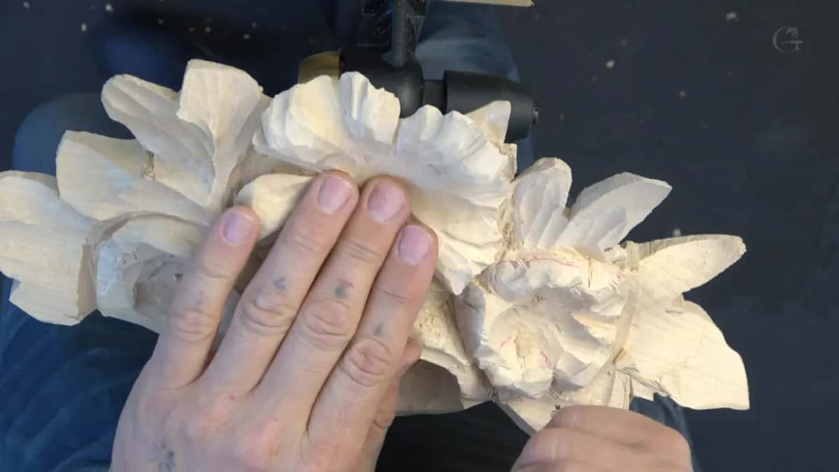 One hand pressed flat on the roughed flowers, red layout lines on the right one
