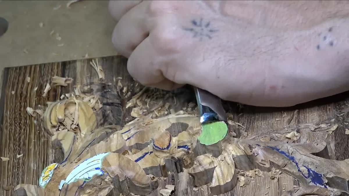 Fist around a gouge, its edge at the green tape