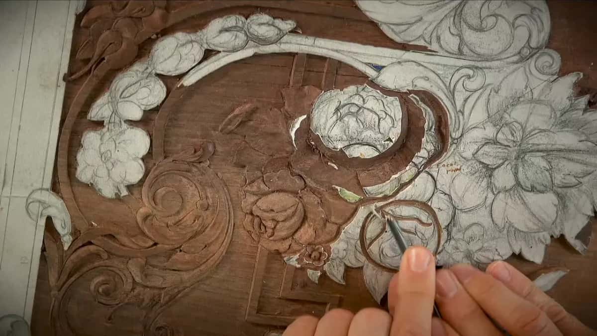Steel tool at the paper-covered circle on the right, a carved rose already done beside it