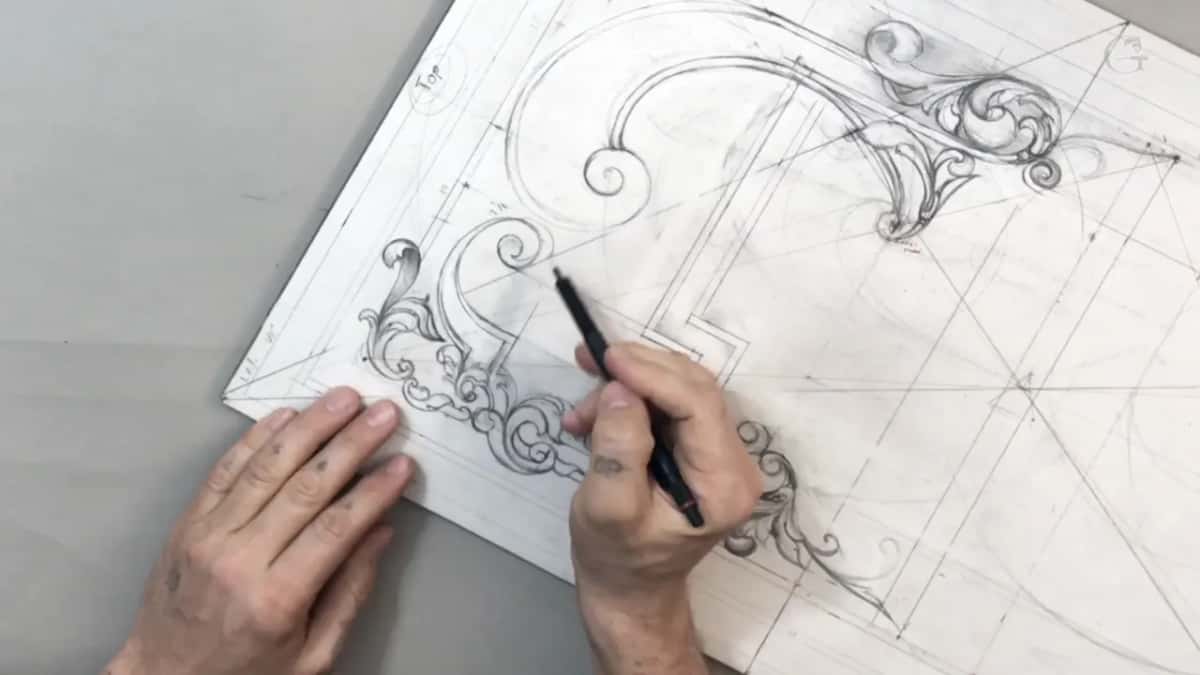 Sheet turned on its corner, one hand flat and one working at the lower scrolls