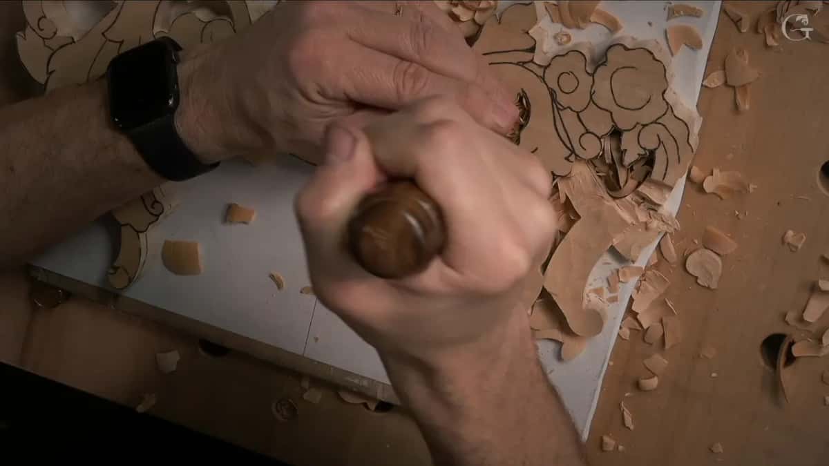 A fist around a round dark handle, the other hand guiding the blade by a pencilled flower