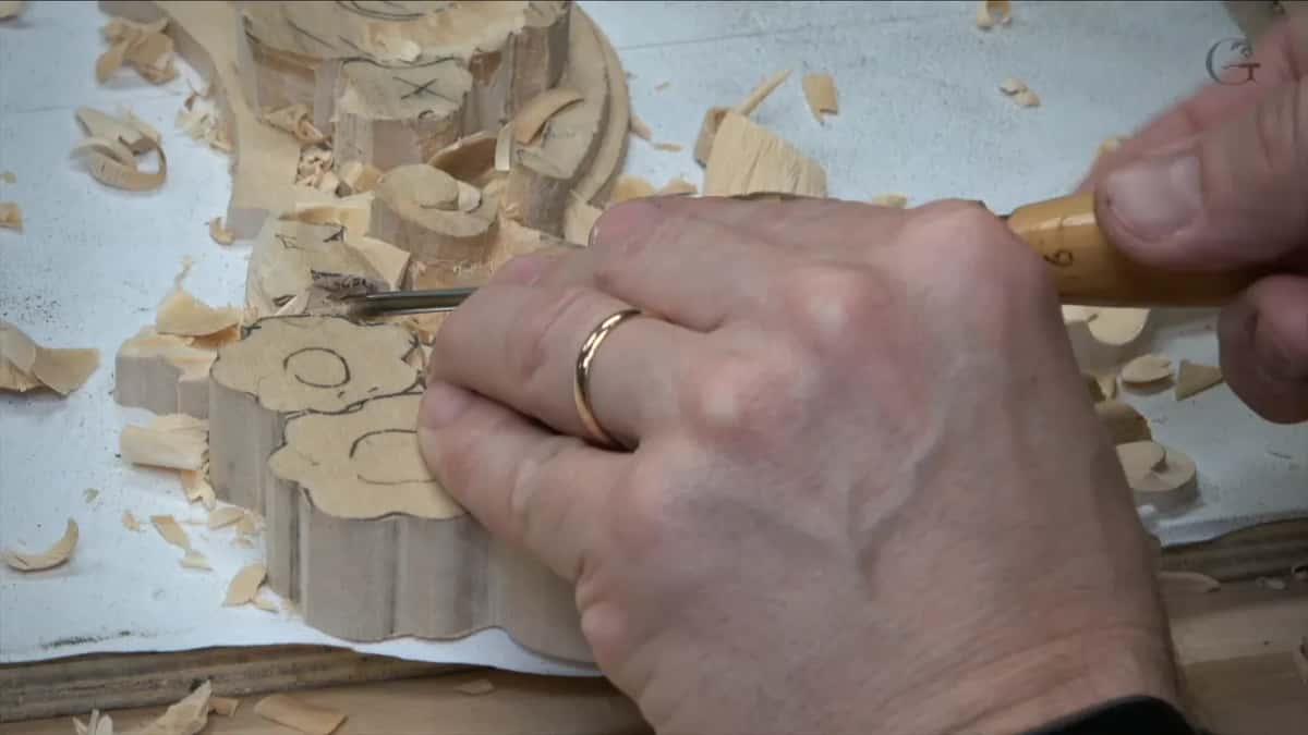 Ringed hand pushing a small gouge into a flower block
