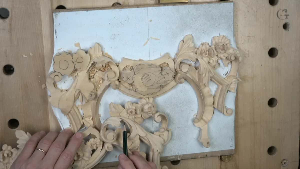 Pencil upright at a carved cluster low on the panel