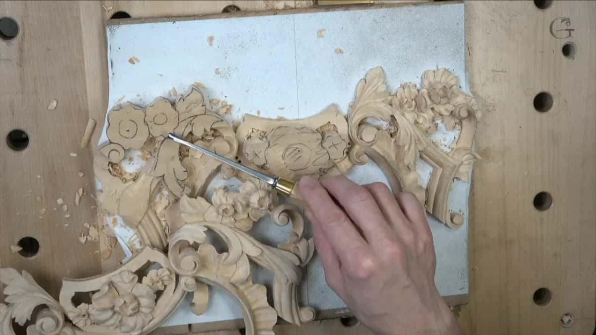 Right hand on a gouge among the left flowers, with the carved right half beyond them