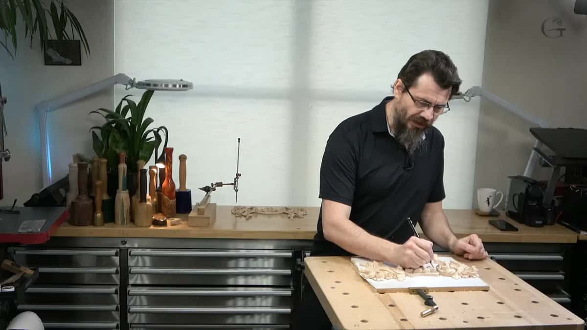 At the bench with a pencil, mallets along the back counter