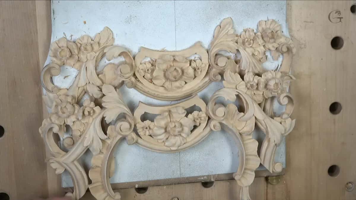 Upper and lower carved pieces together on a white board, laid on a bench top with round holes