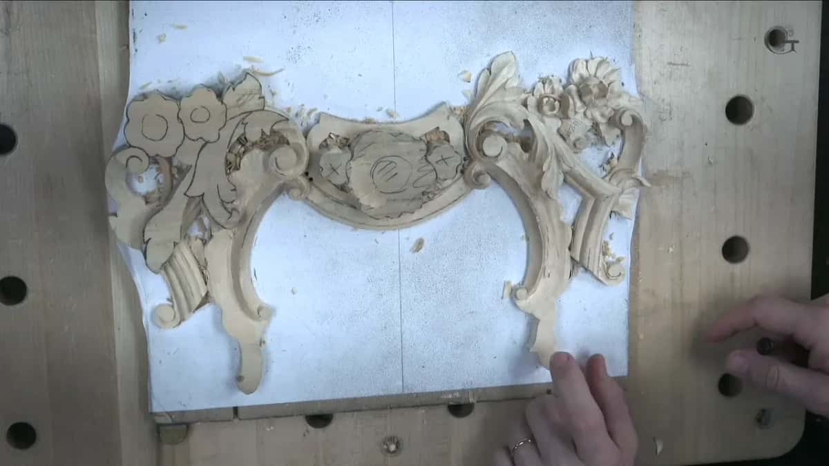 Both hands at the lower corner of the panel, seen from above