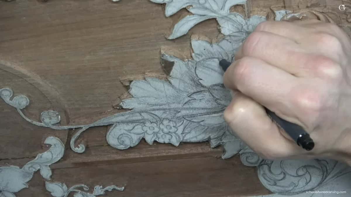 A fist wrapped around a black marker, tracing the drawn leaves beside the flower