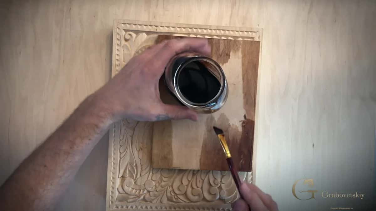 Dark stripes brushed onto a loose board laid over the panel, the jar in one hand