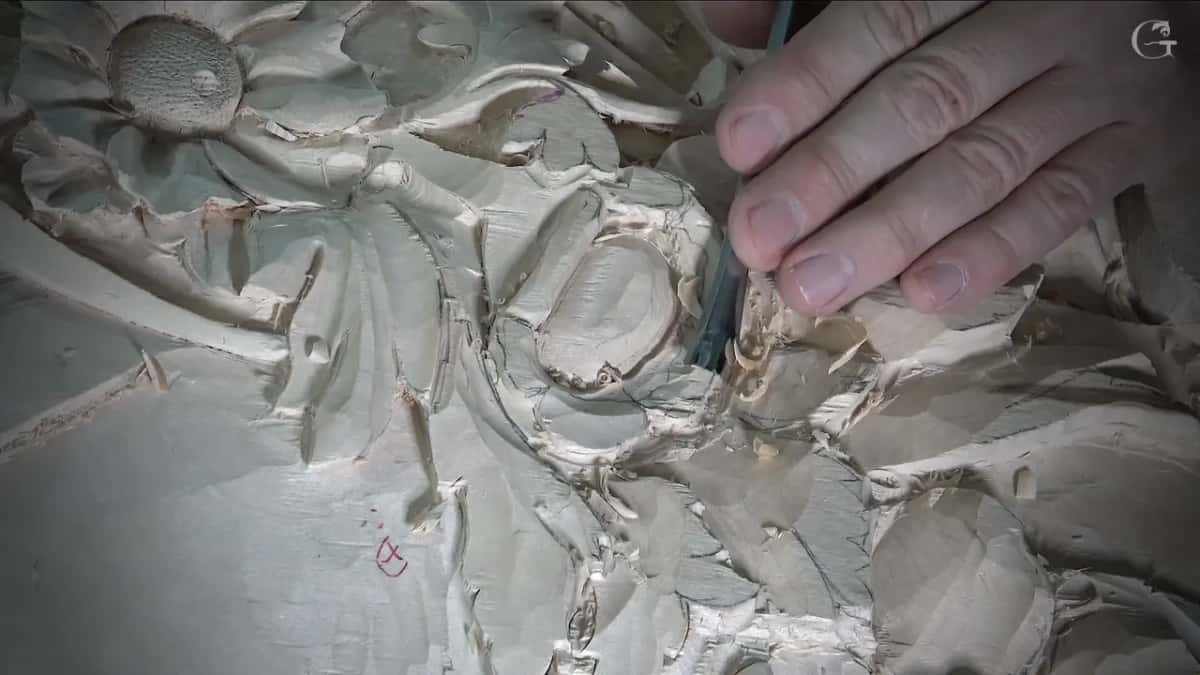 Right hand working a tool along the petal edge while the textured middle of another flower sits above