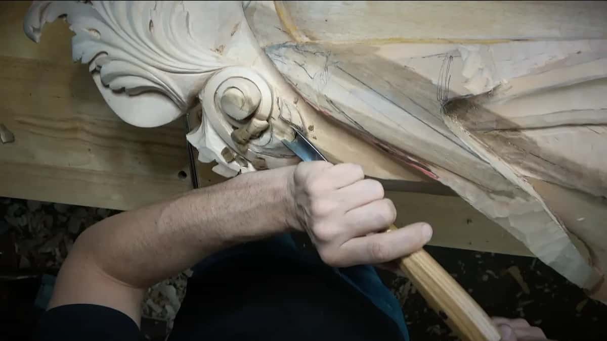 Forearm and gouge angled into the hollow below the volute