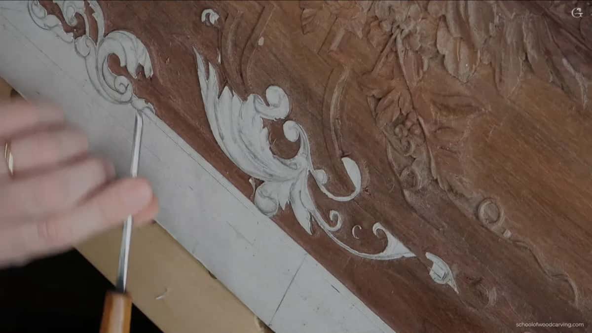 A slim tool with an orange brown handle at the upper left of the scroll, the pattern paper still on