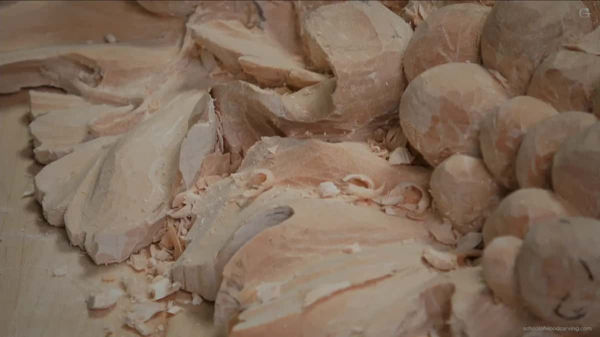 A dark curved groove in one lobe, rough facets and loose chips beside the round grapes