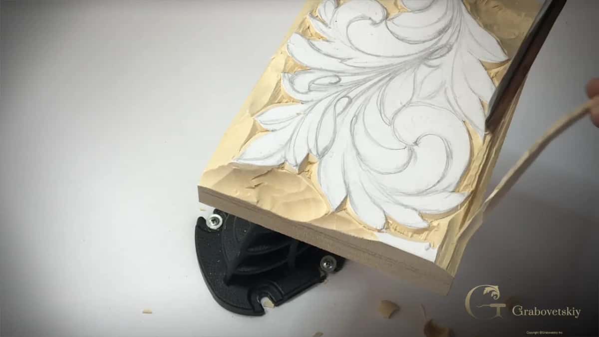 Strip curling away along the edge, with the panel tipped on the round vise base