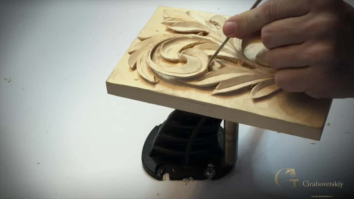 Number 5 slicing inside the curl while the other hand holds the panel still on its stand