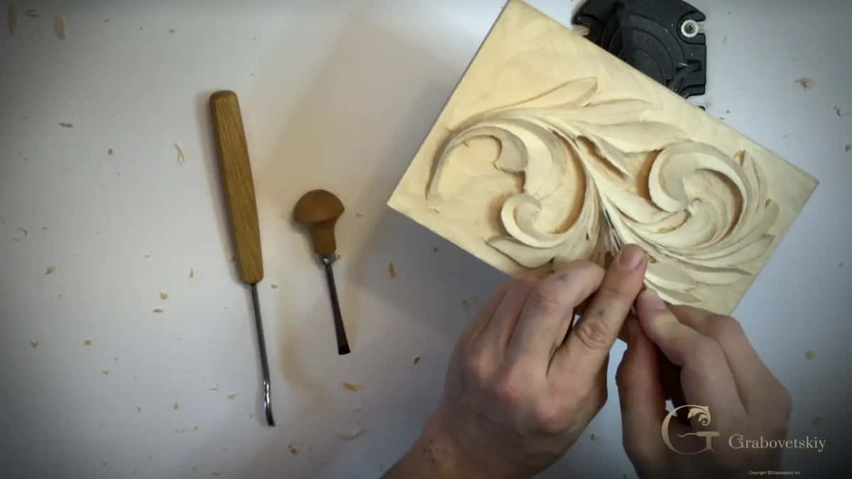 Both hands pinch a tool low on the leaf