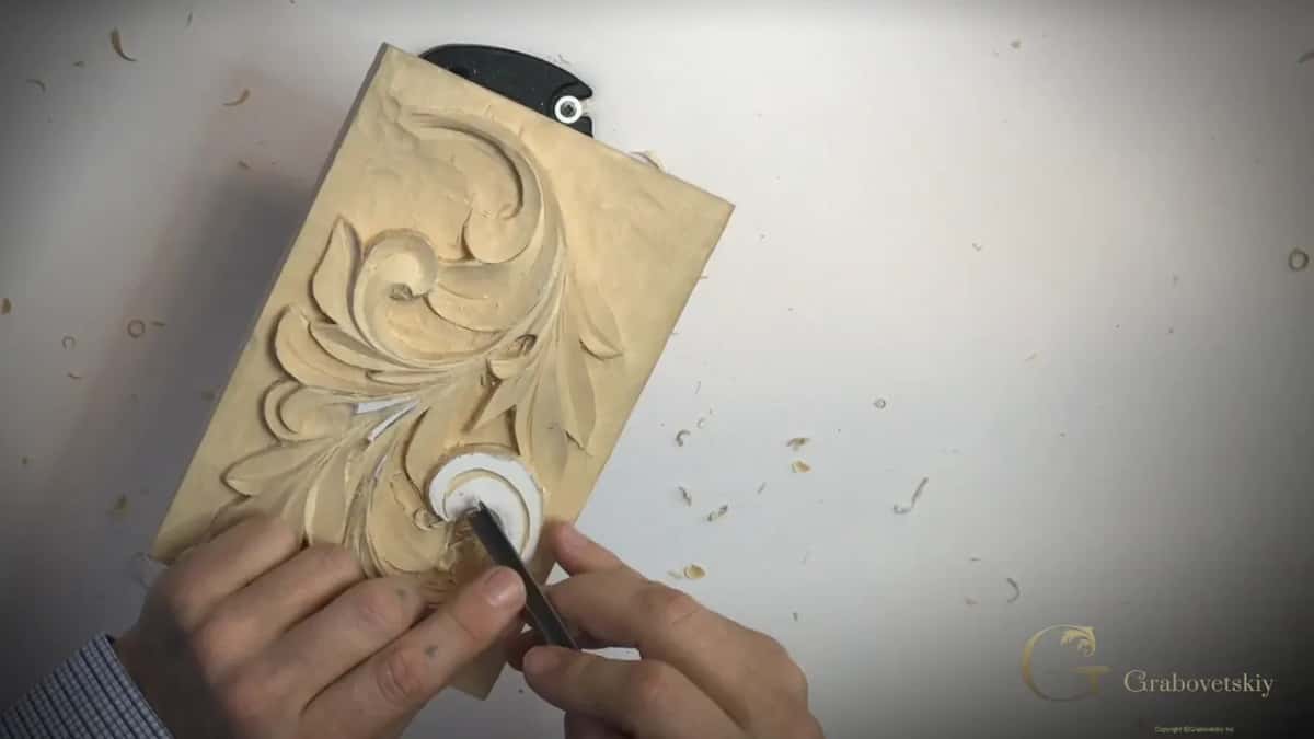 Both hands meet at the white curl, the left on the panel and the right on a short blade