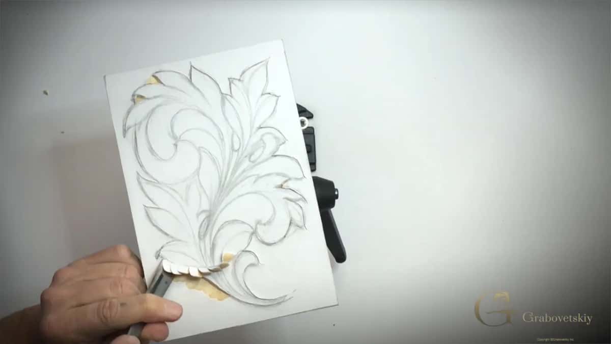 Gouge lifting a curled chip at the base of the leaf, pale knife lines around the drawing