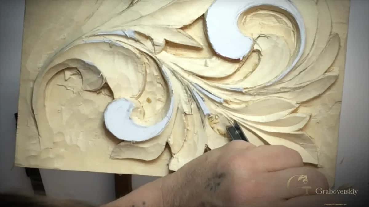 Whole carving from above, one hand at work on its lower edge