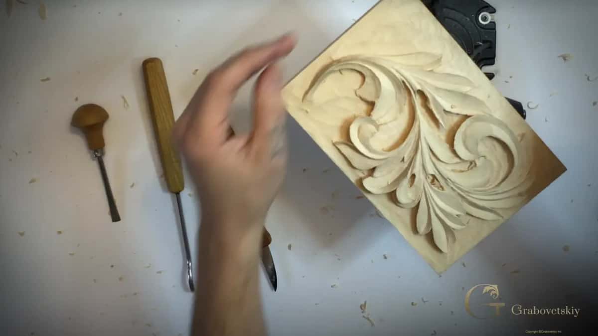 Hand blurred mid stroke, tools waiting on the bench