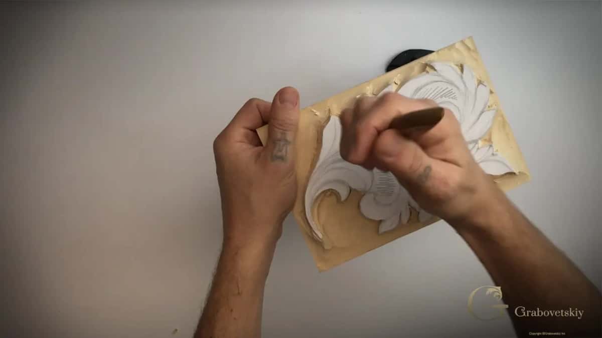 Chip knife in the right hand over the hatched leaf while the left hand holds the panel at its edge