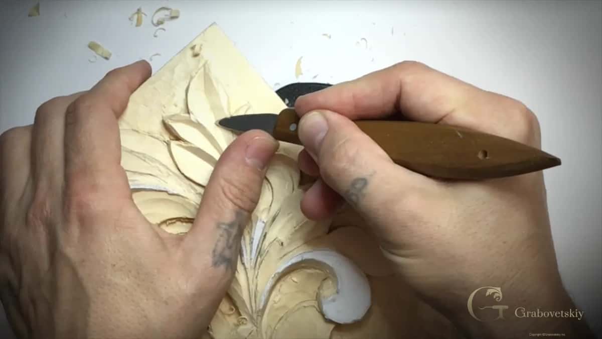 Knife with a long brown handle at a lobe, the left hand bracing the panel