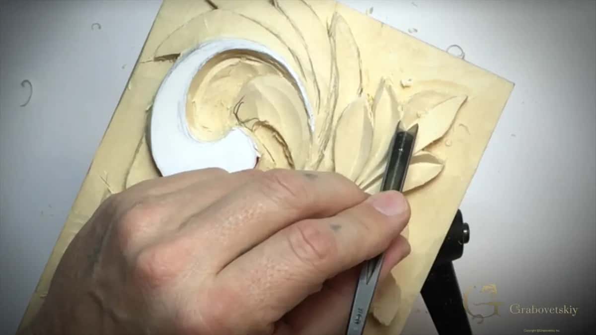 One hand on a V tool with a marked handle, close to the curl