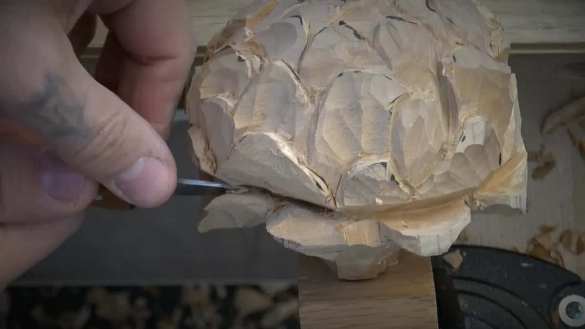 Small tool held under the lower rim of the flower, a black clamp at the foot of the block