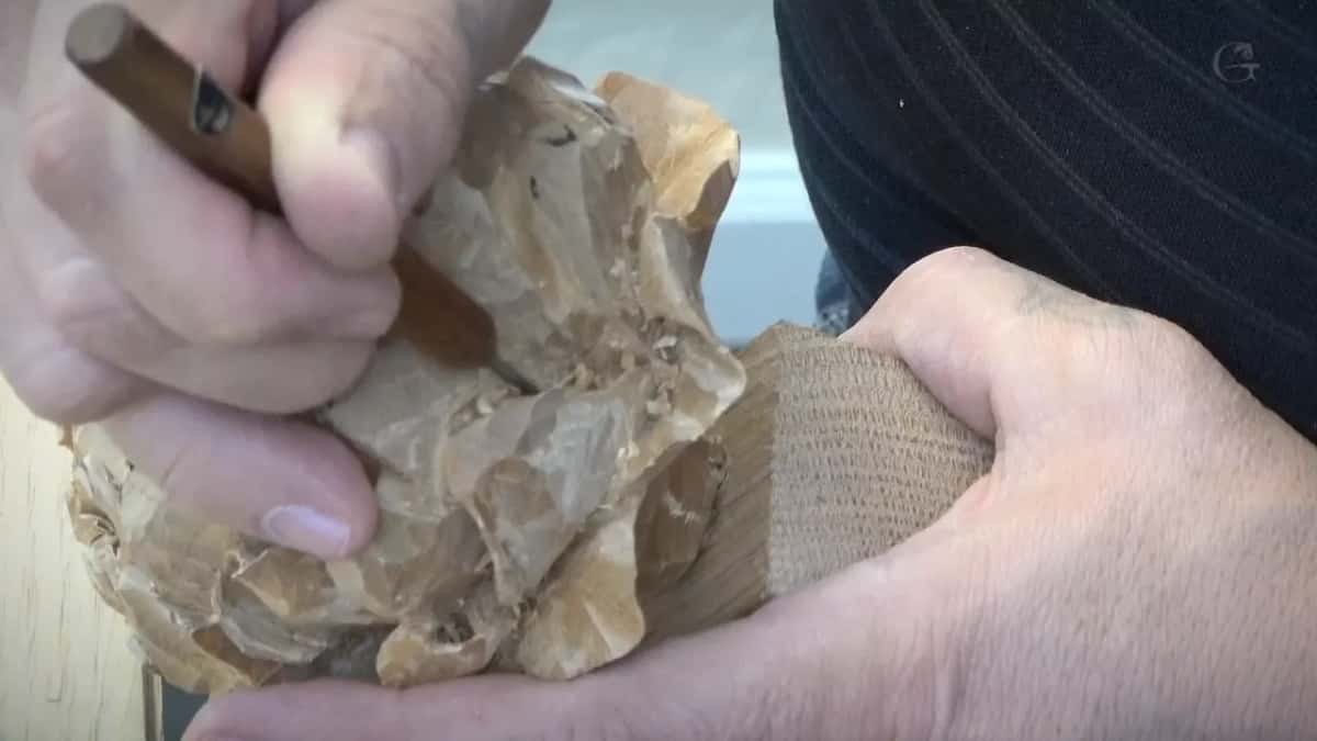 Tool handle gripped in one fist while the other hand holds the flower's block