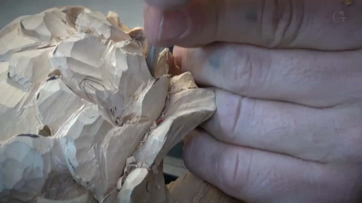 Fingers press a petal edge, the tool tip tucked in by the thumb