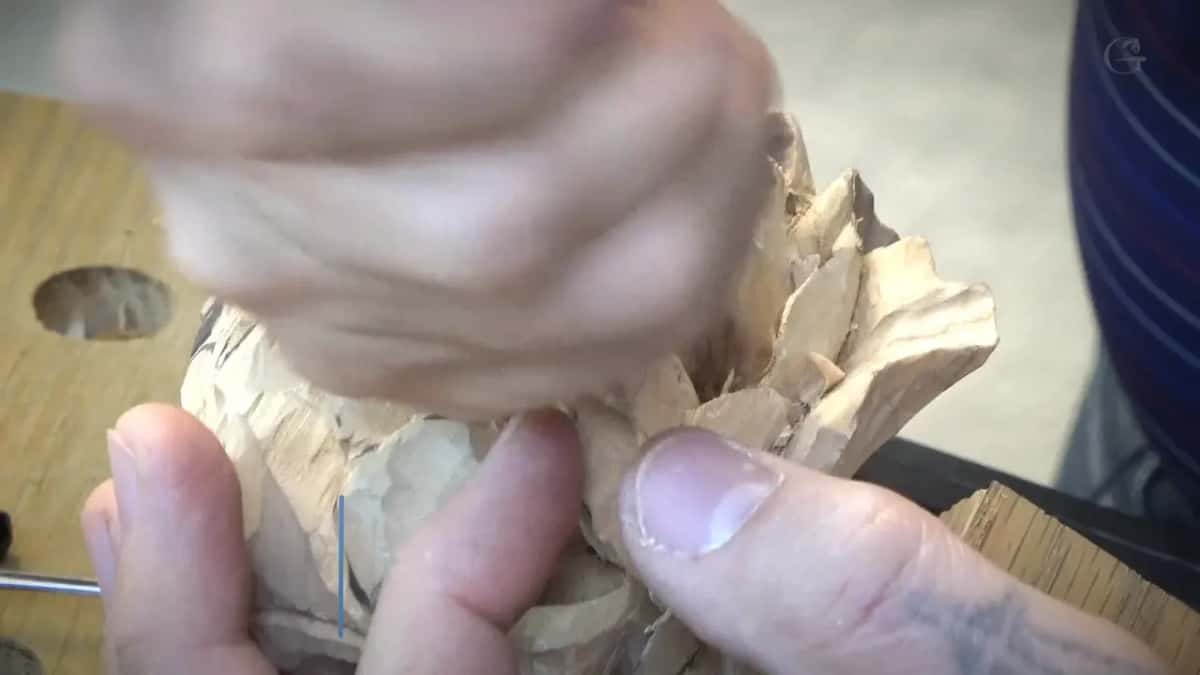 Fingers resting on the carved petals, with a bench dog hole dark just beside them.