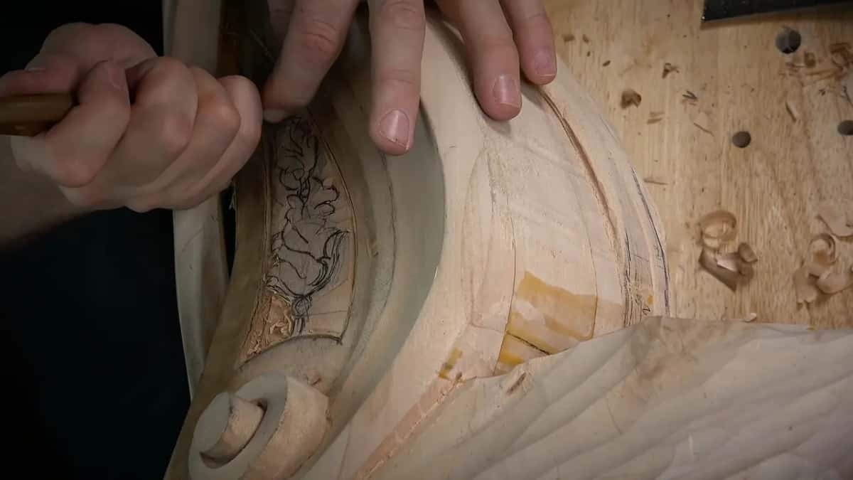 Two hands guide a blade around the sketch