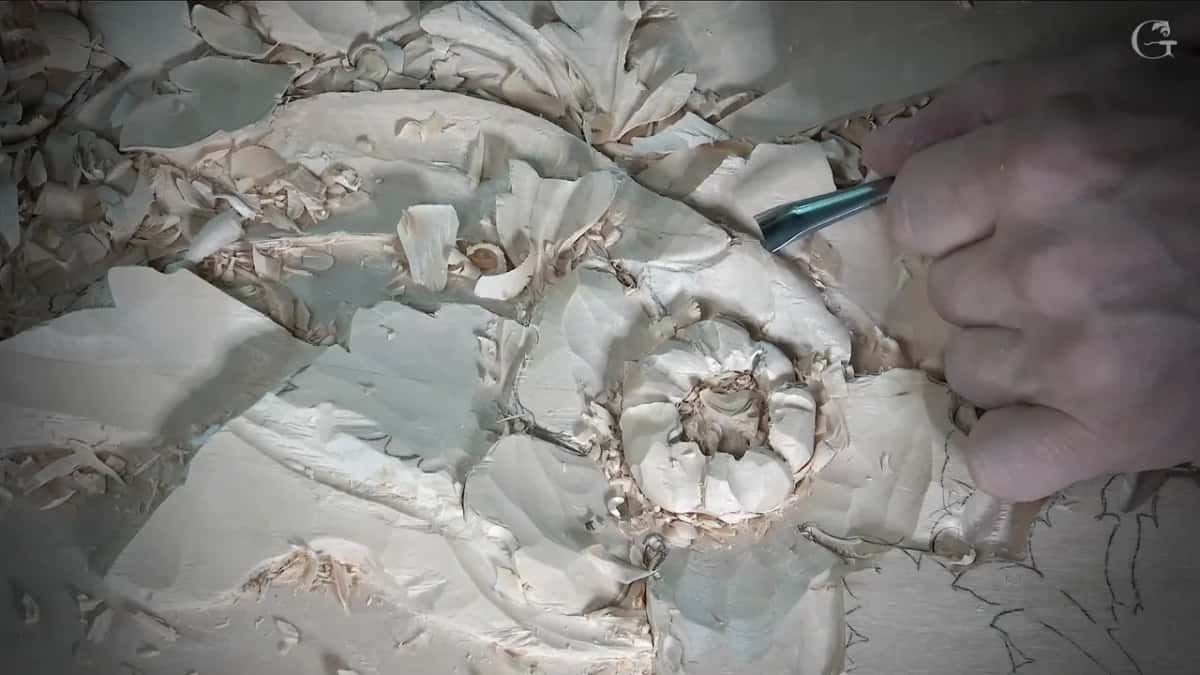 A gouge comes in from the right toward a leaf next to the carved flower, and chips everywhere