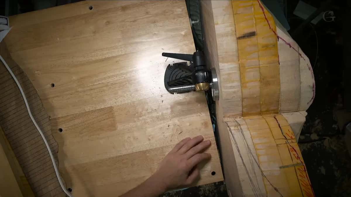 Drilled bench top under one hand, the vise head holding a big block marked in yellow and red