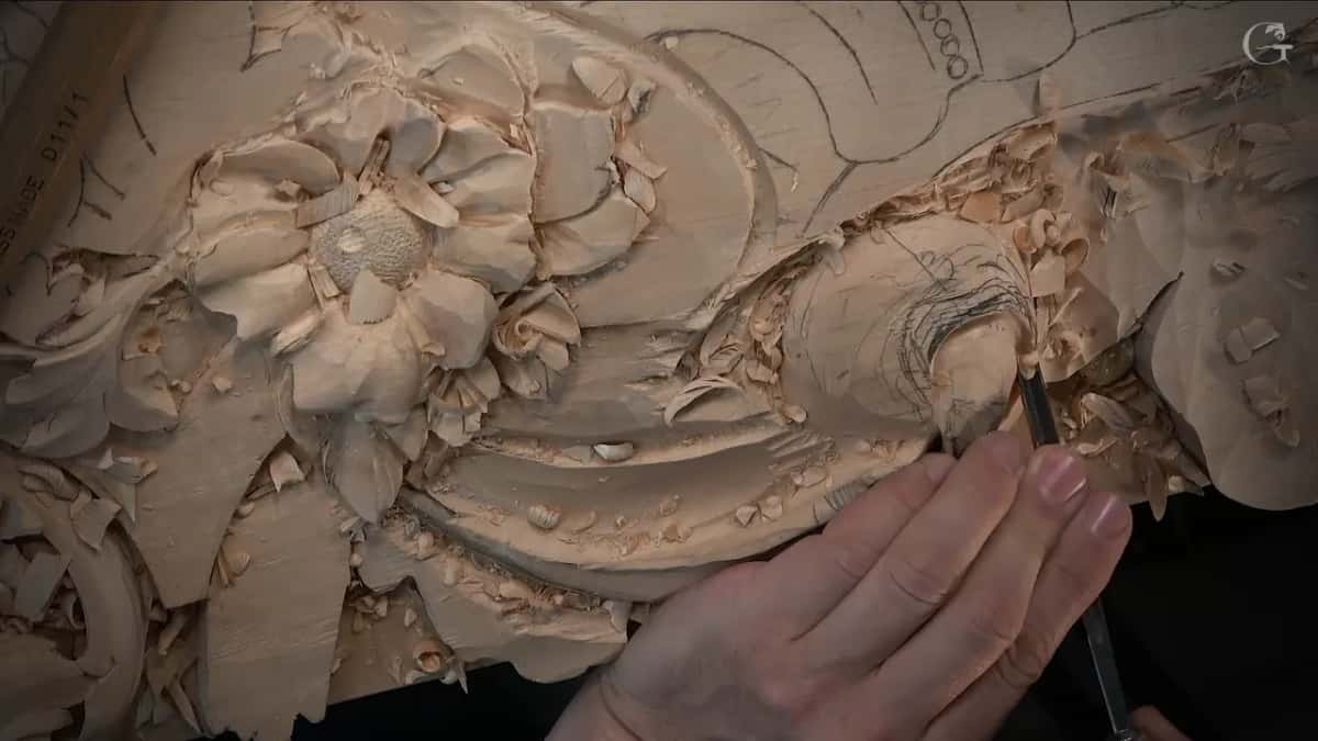 Two hands close together on a slender tool at the edge of the swirl, next to the flower