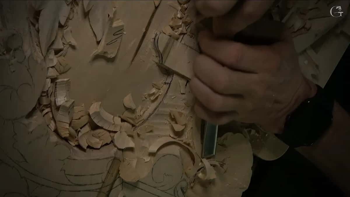 One fist holds a tool upright above the lowered section, pencil lines still showing around it