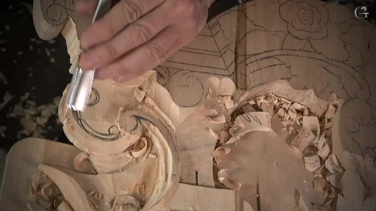 A wide U gouge beside fresh pencil lines on the volute