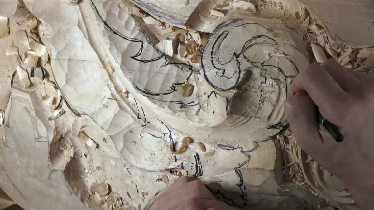 Close to the volute, a hand draws over the traced lines in marker.