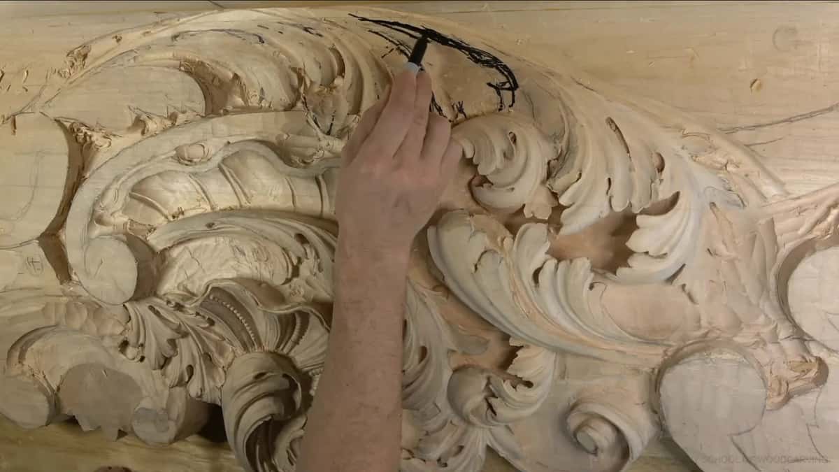 Marker in hand, drawing a long curve where the next leaf will go, the carved scrolls below it.