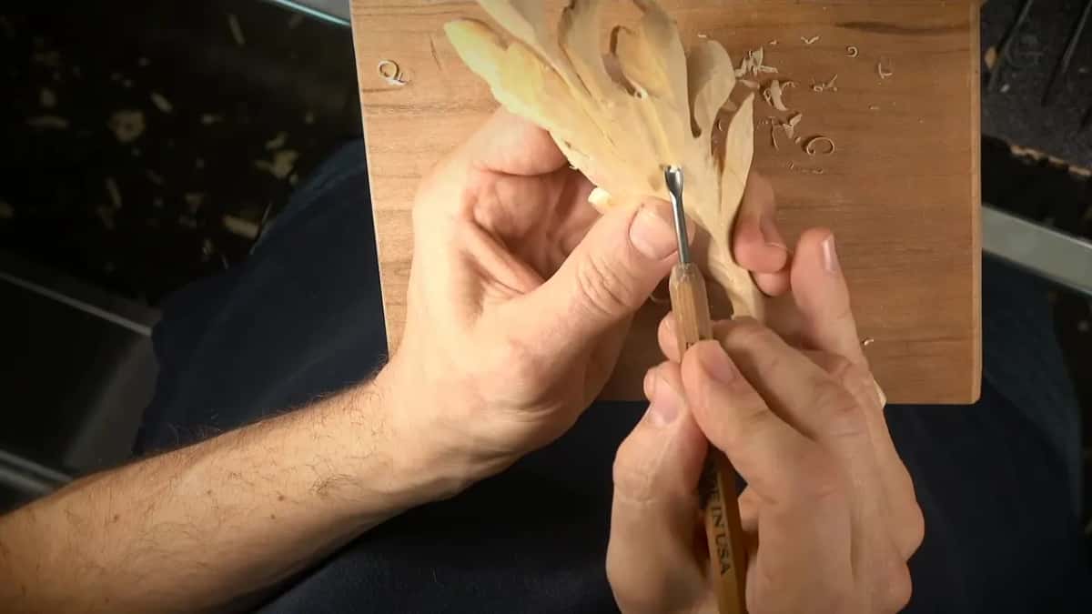 Fingers behind the leaf while a small tool works its center