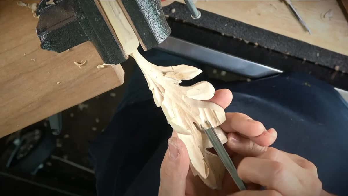 Straight narrow gouge slipping under a lobe, the leaf hanging from the vise
